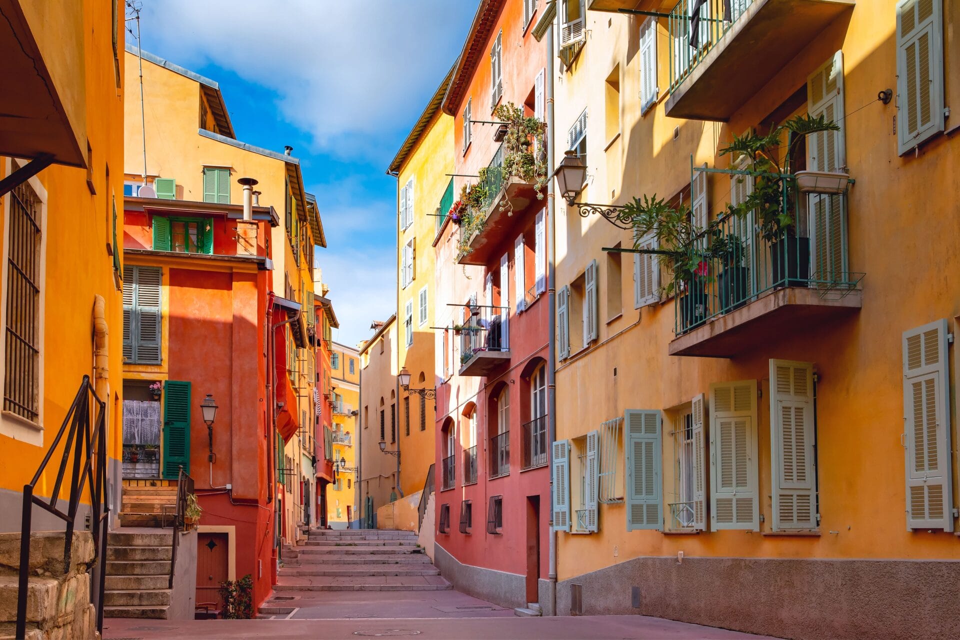 France: Sunny colourful historical houses in the Old Town of Nice in the French Riviera with warm tones and clear daylight illuminating the street.